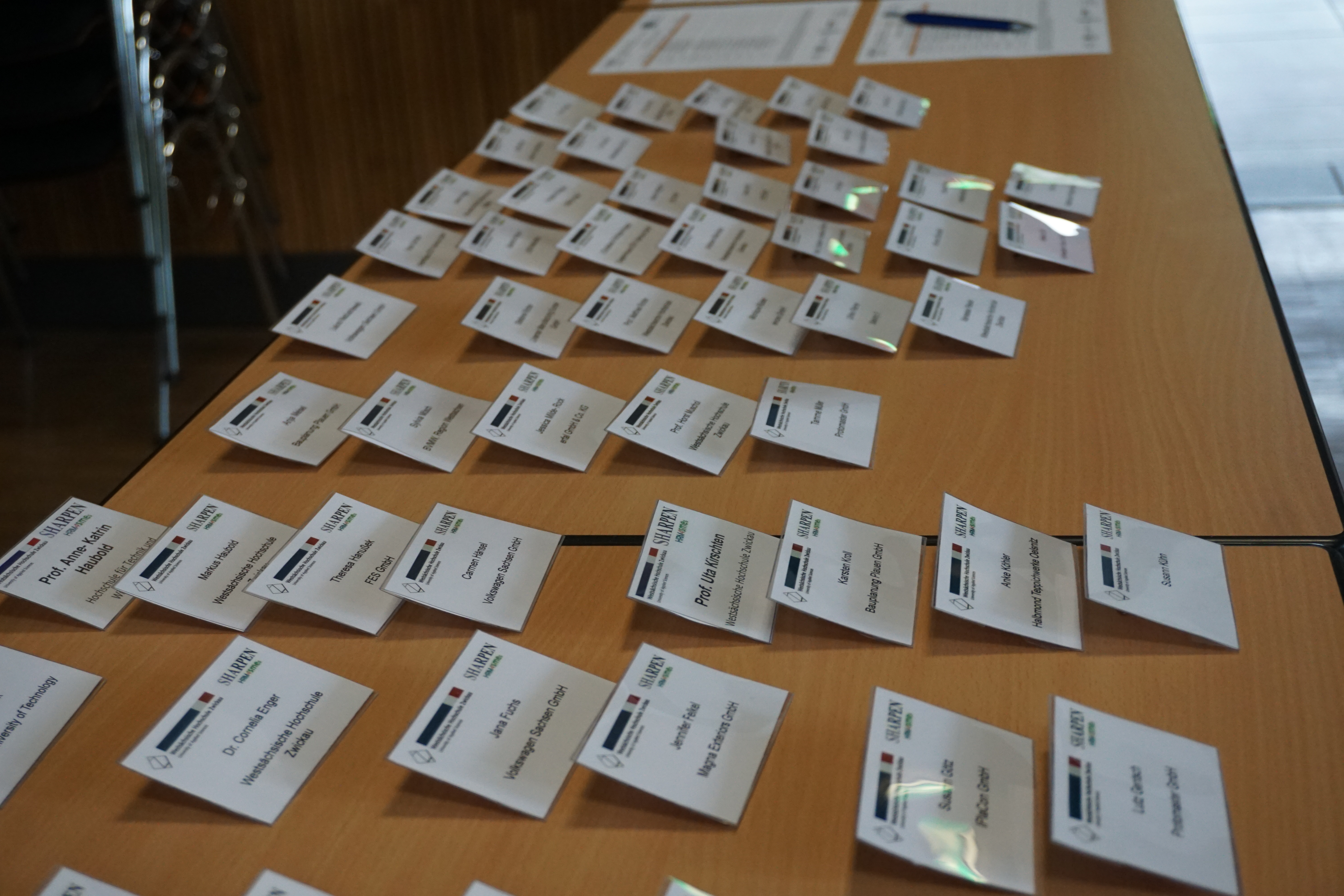 Foto: Eine Tischreihe auf diesen vorsortiert die Namenschilder für die Teilnehmer liegen.