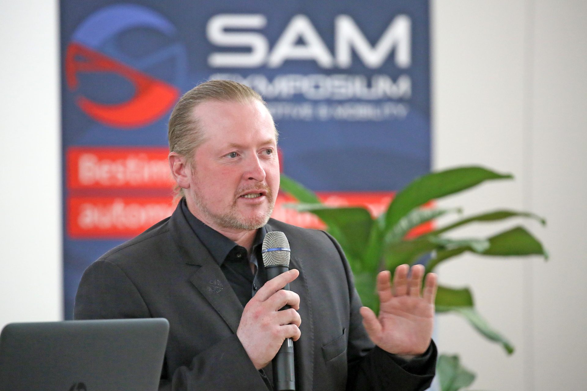 Foto: Joey Kelly spricht in ein Mikrofon zum 3. Symposium Automotive & Mobility (SAM)