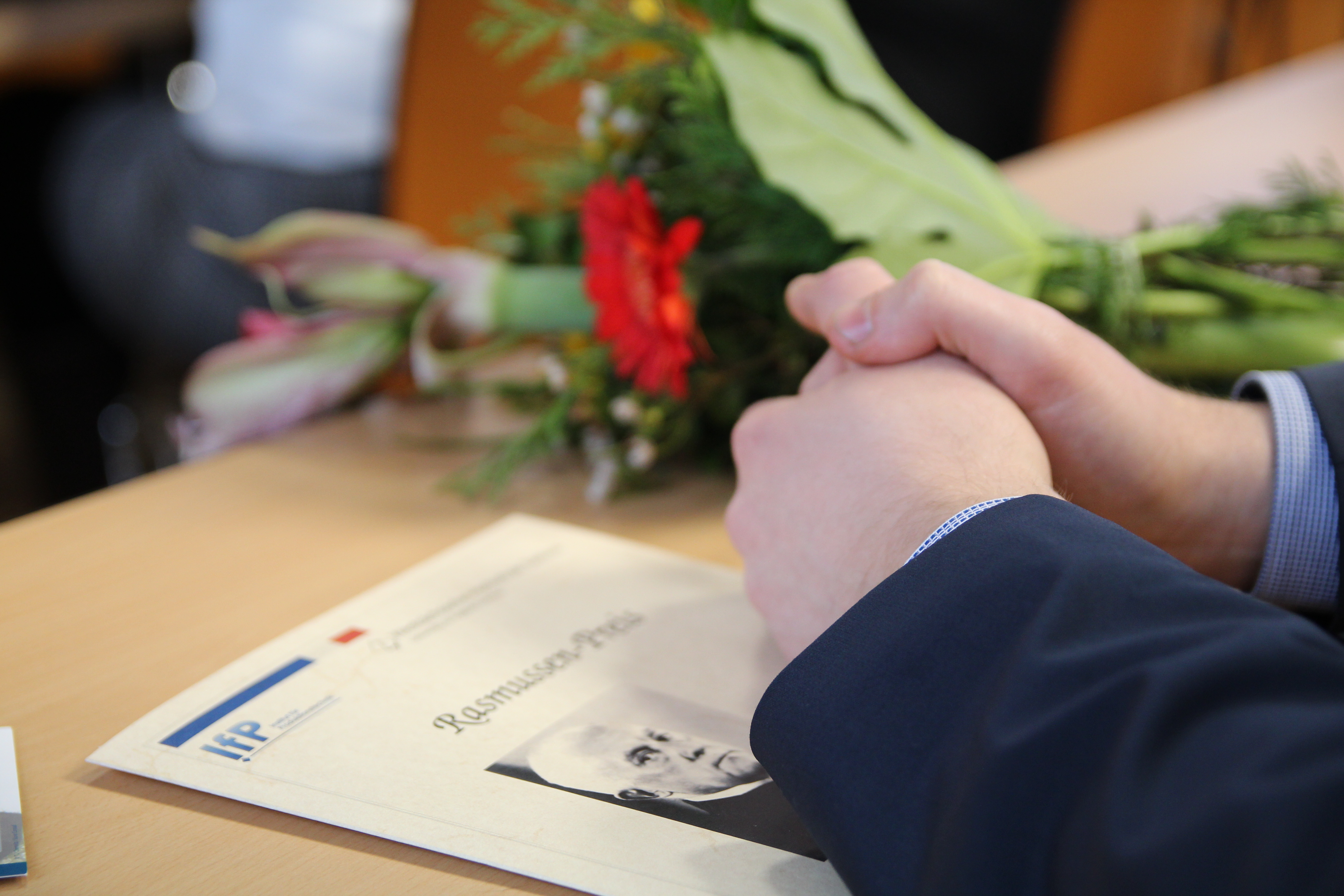 Foto: Zwei Hände liegen zusammengefaltet über einer Informationsbroschüre auf einem Tisch.
