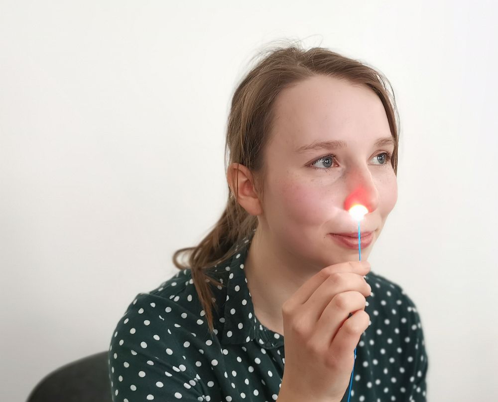 Foto: Eine Wissenschaftler hält einen leuchtenden demonstrator in ein Nasenloch. 