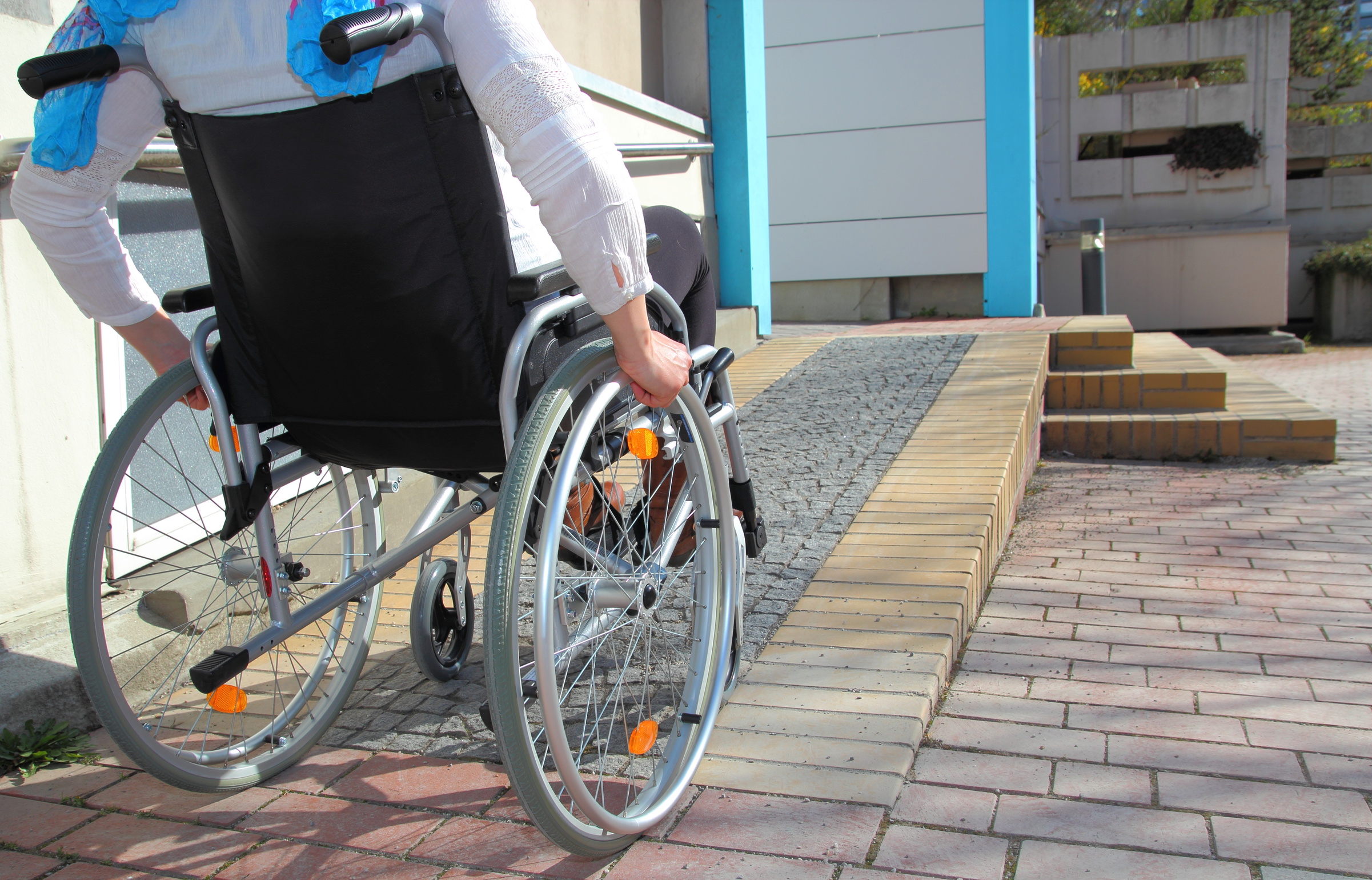 Eine Person im Rollstuhl fährt eine Rollstuhlrampe herauf