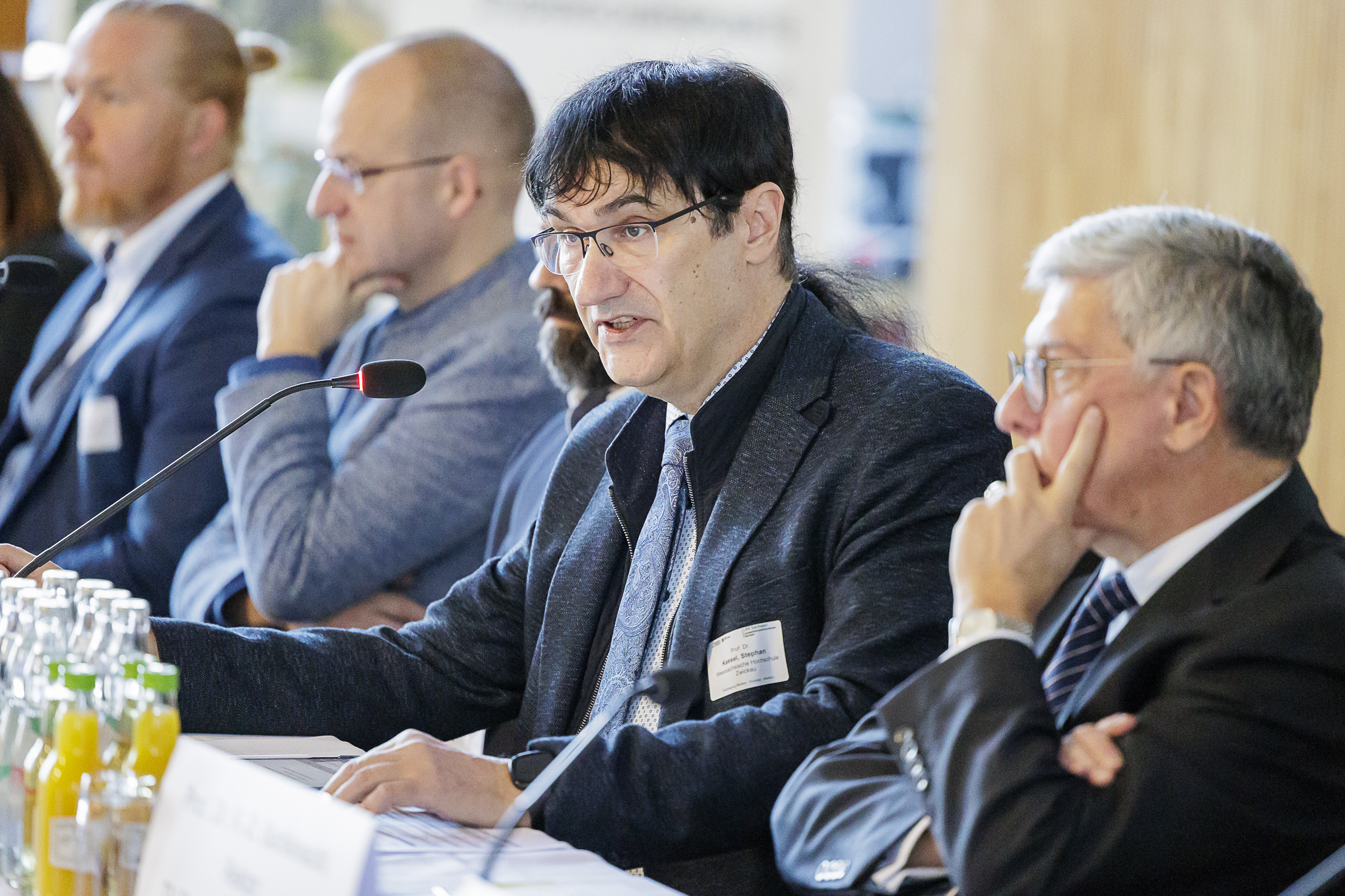 WHZ-Rektor Stephan Kassel sitzt mit weiteren Teilnehmern an einem Besprechungstisch, vor Ihnen Namensschilder. 