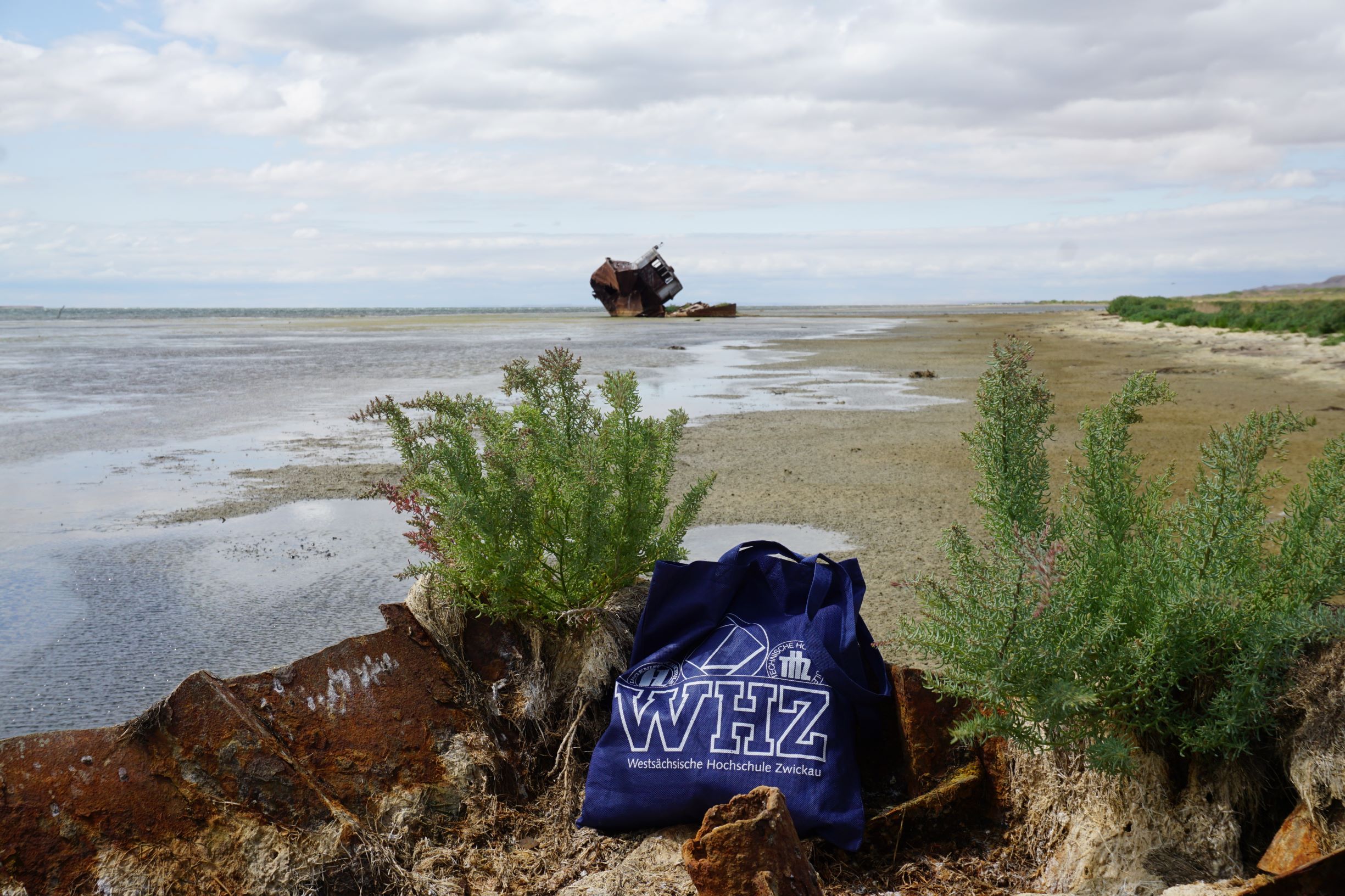 Ein WHZ-Beutel liegt am Ufer des ausgetrockneten Aral-Sees. Im Hintergrund ein Schiffswrack. 