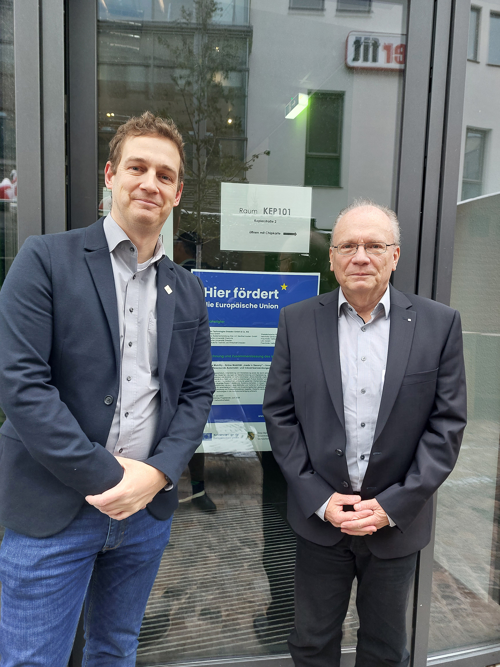 Prof. Christoph Laroque und Prof. Peter Hartmann stehen vor dem Eingang des Fraunhofer AZOM. 