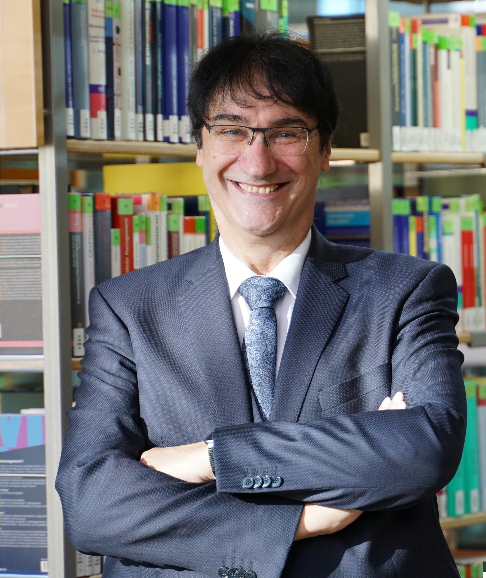 Portraitbild Prof. Stephan Kassel in Hochschulbibliothek, im Hintergrund Bücherregale
