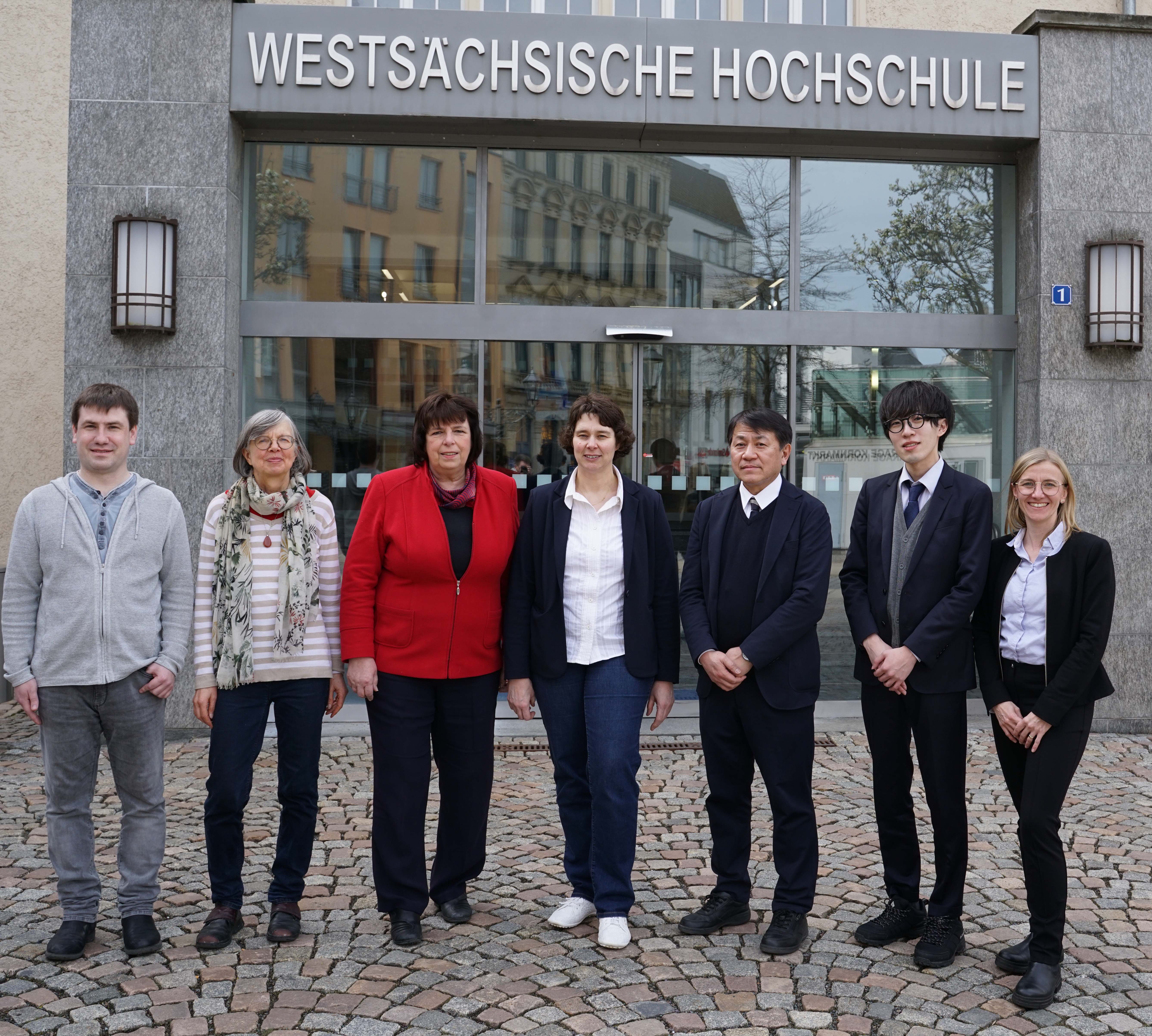 Eine Gruppe von Personen steht vor dem Eingang der Westsächsischen Hochschule Zwickau