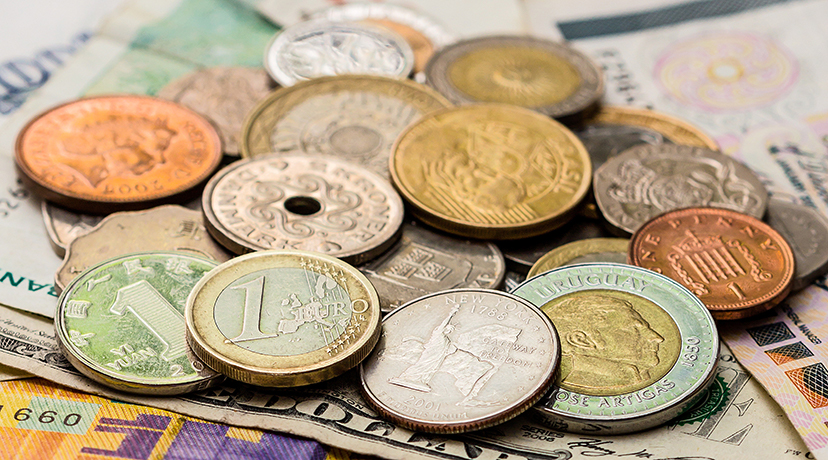 Foto: Auf Banknoten liegend, ein Häufchen unterschiedlicher Geldmünzen verschiedener Länder. 